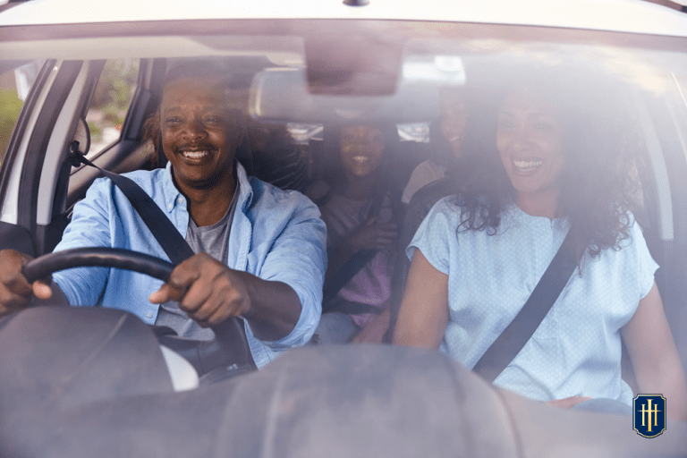 Uma família de 5 pessoas, dentro de um carro, felizes, indo viajar.