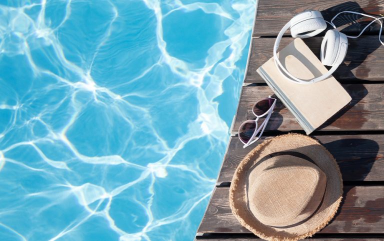 A imagem mostra alguns acessórios na beira da piscina e um fone de ouvido, demonstrando que o indivíduo descansará escutando música.