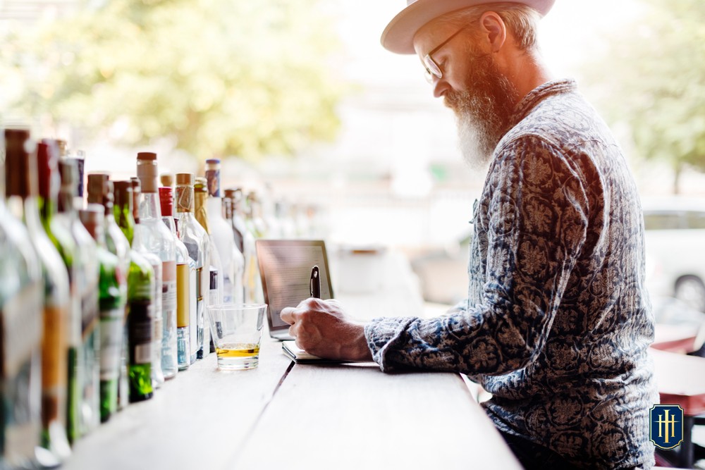 Um homem com várias garrafas de cachaça na frente no bar do Hotel Internacional Gravatal