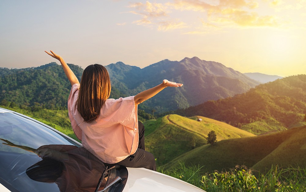 A imagem mostra uma mulher em uma linda paisagem, aproveitando seus roteiros turísticos.