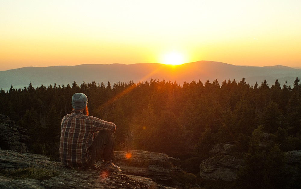 Homem sentado na natureza, observando as belezas naturais