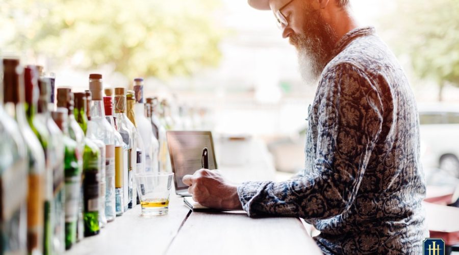 Um homem com várias garrafas de cachaça na frente no bar do Hotel Internacional Gravatal