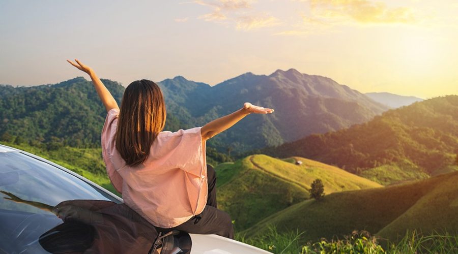 A imagem mostra uma mulher em uma linda paisagem, aproveitando seus roteiros turísticos.