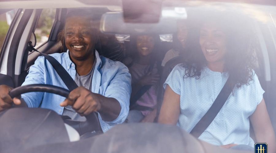 Uma família de 5 pessoas, dentro de um carro, felizes, indo viajar.