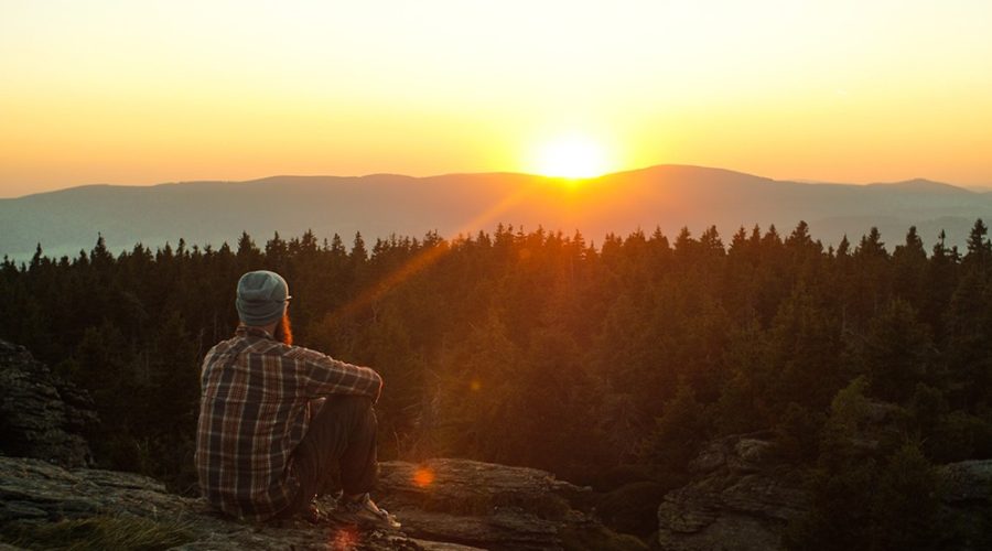 Homem sentado na natureza, observando as belezas naturais