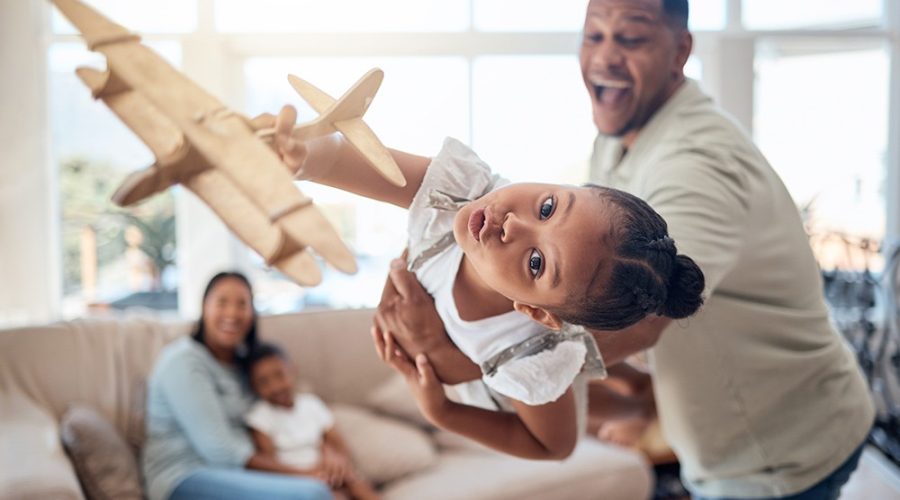 Pai e filha brincando com avião, ambos se divertindo, criando uma memória afetiva